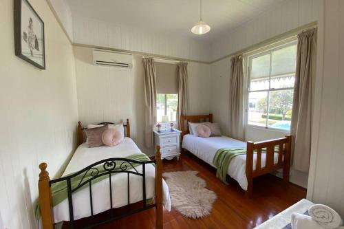 土乌巴Ashbrooke Cottage的一间卧室设有两张床和窗户。