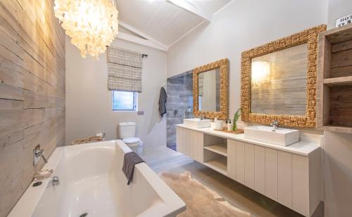 滨海肯顿Driftwood by The Oyster Collection的带浴缸、两个盥洗盆和镜子的浴室