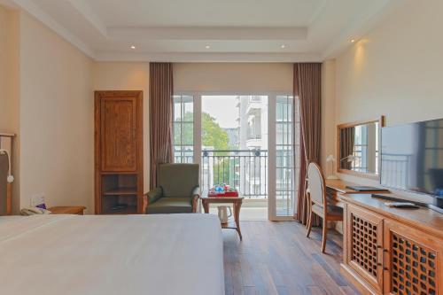 胡志明市黄兰酒店的一间带一张床和一张书桌的卧室以及一个阳台