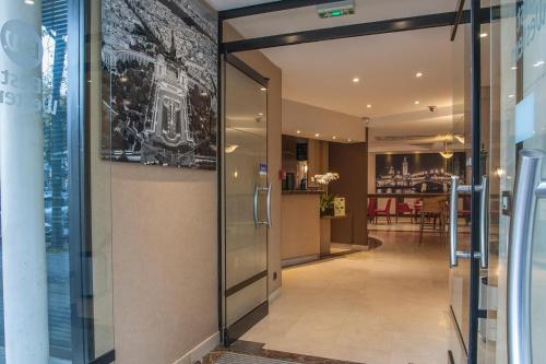 巴黎贝斯特韦斯特特洛加德洛酒店的走廊上设有玻璃门,通往餐厅