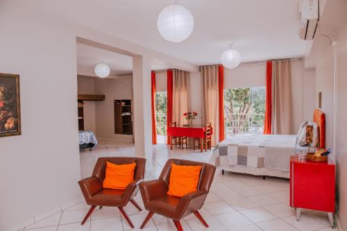 伊通比亚拉贝拉里约宾馆的一间卧室配有两把椅子和一张带橙色枕头的床
