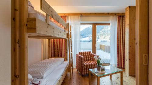 塞斯托莱纳家庭度假酒店的酒店客房配有双层床和椅子。
