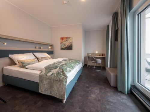 布吕尔RS-HOTEL - smart luxury hotel & apartments, contactless and inspected的一间卧室配有一张床、一张书桌和一个窗户。