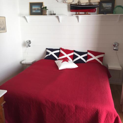 哥德堡Peaceful Cottage的一间卧室配有红色的床和四个枕头