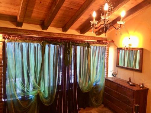 VátosErmones Emerald Villa的配有窗帘、梳妆台和吊灯的房间