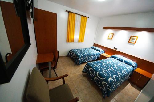 卡斯佩Hostal Restaurante El Surtidor的酒店客房设有两张床和一张桌子。