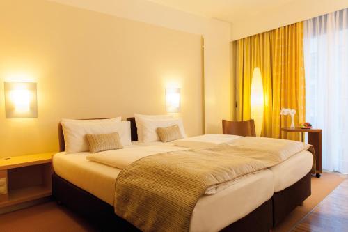 柏林centrovital Hotel Berlin的酒店客房配有一张带枕头的大床