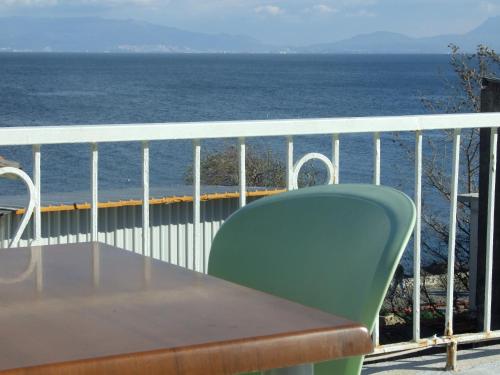 穆达尼亚穆达尼亚酒店的俯瞰大海的阳台配有一张桌子和一把绿色椅子