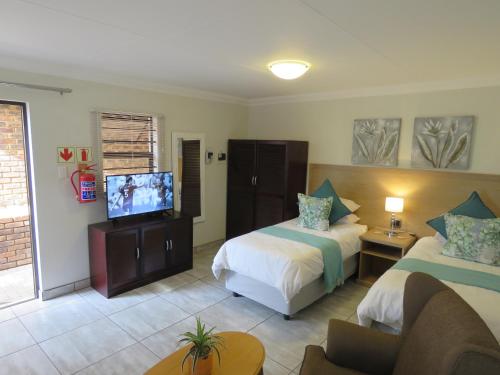 比勒陀利亚Sunbird Garden Cottage的酒店客房设有两张床和一台平面电视。