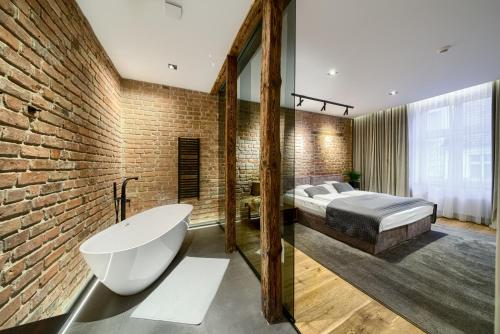 海乌姆诺克尔明斯基公寓的卧室配有一张床和一个浴缸,毗邻砖墙
