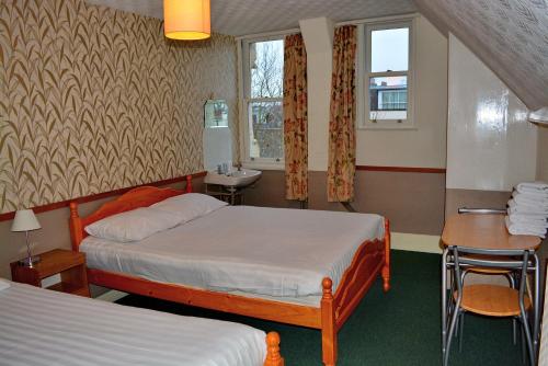 伦敦伦敦维森特酒店的酒店客房设有两张床、一张桌子和一个水槽