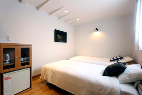 大阪Hotel 3 O'Clock Tennoji的一间卧室设有两张床,墙上配有电视。