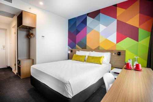 布里斯班ibis Styles Brisbane Elizabeth Street的酒店客房设有床和色彩缤纷的墙壁。