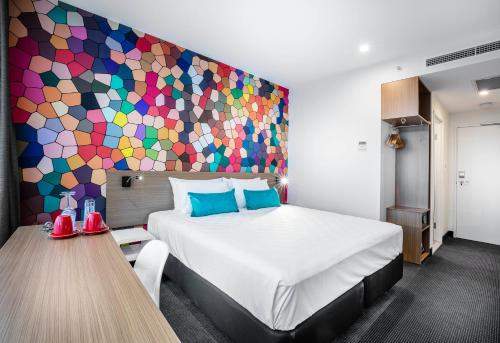 布里斯班ibis Styles Brisbane Elizabeth Street的一间卧室设有一张大床和色彩缤纷的墙壁