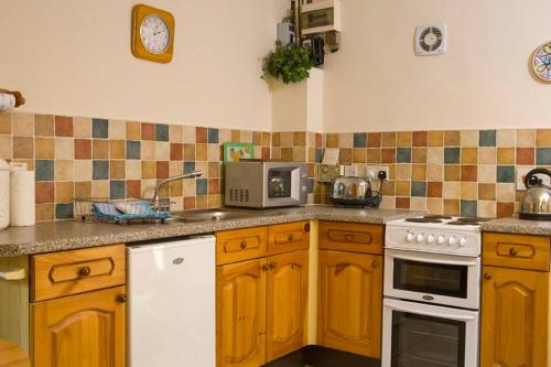 切尔滕纳姆Sherbourne Cottage, Seven Springs Cottages的厨房配有木制橱柜和白色炉灶烤箱。