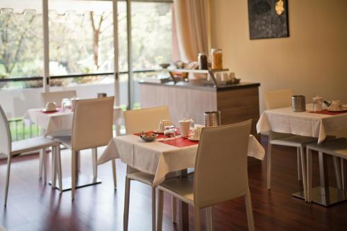巴斯基里奥Botton D'Oro 2 Rozzano的餐厅设有白色的桌椅和窗户。