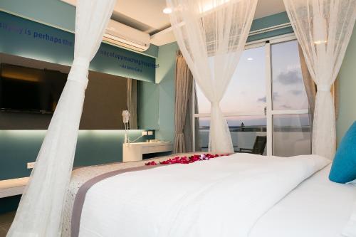 垦丁大街垦丁白沙滩旅店的卧室配有一张大白色床和窗户