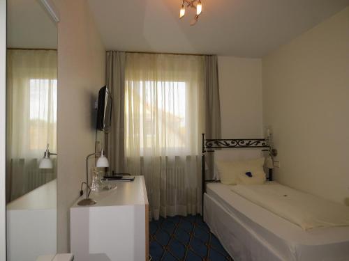 乌尔丁根-米赫尔霍芬Hotel & Restaurant Mainaublick的一间卧室配有床、水槽和镜子