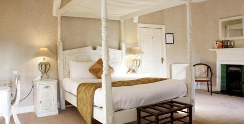 泰恩河畔纽卡斯尔Otterburn Castle的卧室配有白色的天蓬床和壁炉