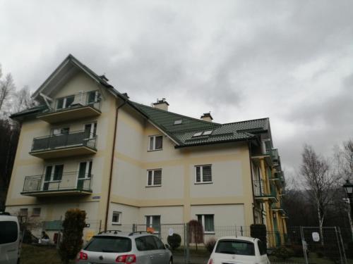 乌斯特龙Apartament Równica的两辆汽车停在房子前面的房子