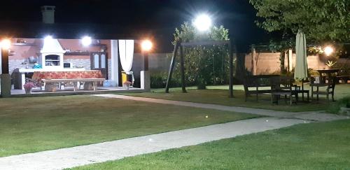桑亨霍Hotel Cachada的夜间公园,设有长凳和桌子