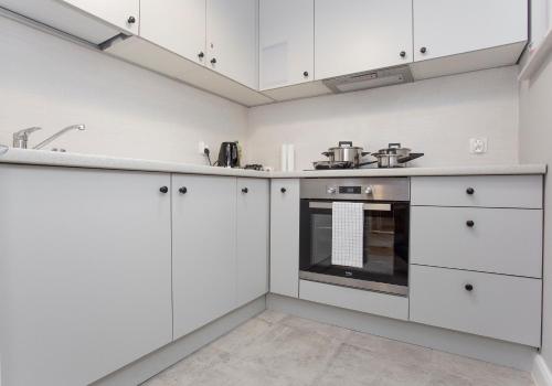 比亚韦斯托克CR Apartament Broniewskiego 15的厨房配有白色橱柜和烤箱。