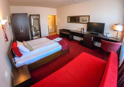 锡比乌Casa Veche的一间卧室配有一张床、一张桌子和一张红色的沙发