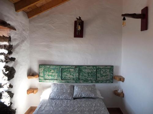 El Pinar del HierroCasa Rural Los Santillos的一间卧室配有一张带绿色床头板的床和时钟