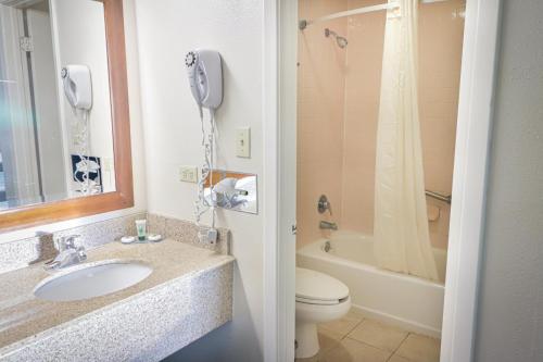 圣安东尼奥University Inn & Suites的一间带水槽和卫生间的浴室以及一部电话
