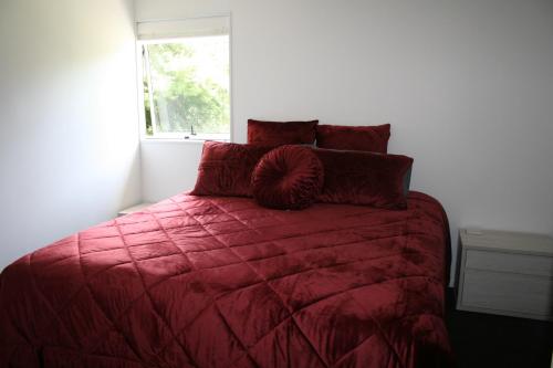 OkoroireBridgehaven Guesthouse的一间卧室配有一张带红色棉被的床和窗户。