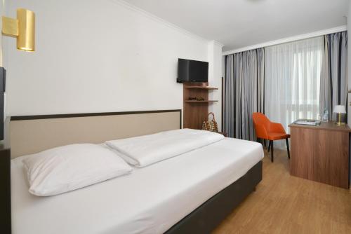 慕尼黑Hotel Aurbacher Hof GmbH的一间卧室配有一张床、一张桌子和一把椅子