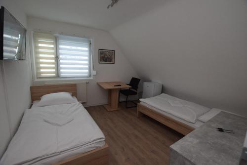斯图加特AB Möhringen Messe Zimmer的客房设有两张床、一张桌子和一个窗户。