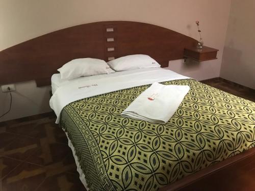 齐克拉约Tamaris Hotel的一间卧室配有一张大床和木制床头板