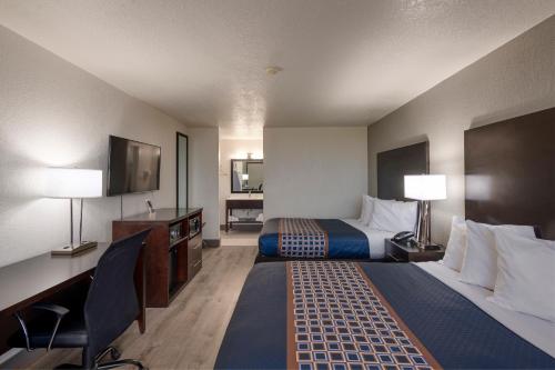 奥兰多Hotel Monreale Express International Drive Orlando的酒店客房设有两张床、一张桌子和一台电视。