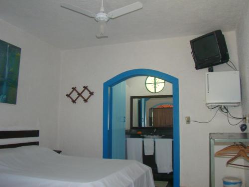 卡舒埃拉斯迪马卡库Pousada do Escultor的一间卧室配有一张床、镜子和电视