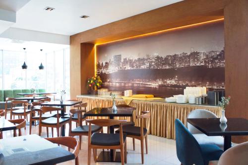 利马住所酒店的餐厅设有桌椅,墙上挂着一幅大画