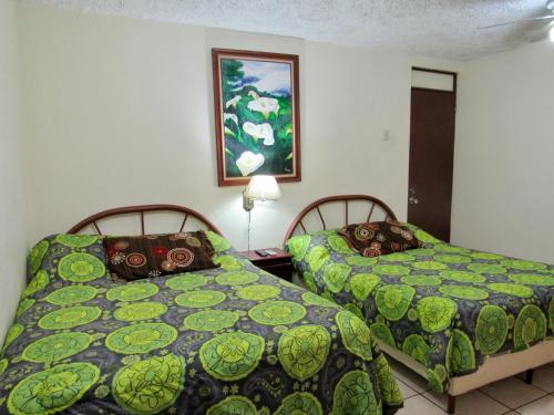 阿拉胡埃拉拉瓜里亚套房酒店的卧室配有两张床,墙上挂着一幅画