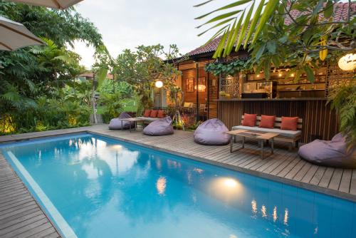 坎古Pangkung Sari Bed and Breakfast的一座带紫色枕头的游泳池位于房子旁边
