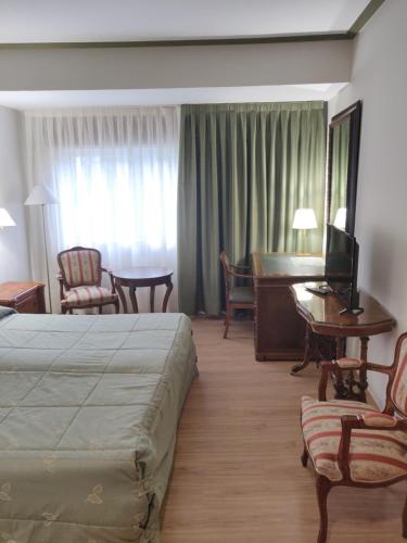 帕德隆谢夫里维拉酒店的酒店客房配有一张床铺、一张桌子和一张书桌。