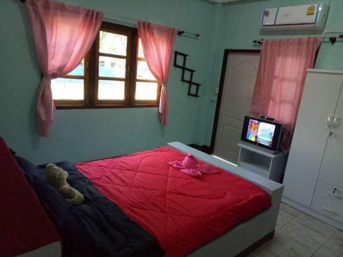 Ban Huai SalokWangtong Resort 2的一间卧室,配有一张红色的床,上面有泰迪熊