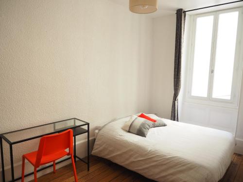 瓦朗斯Appartement le st jean - centre historique的一间卧室配有一张床和一张红色椅子