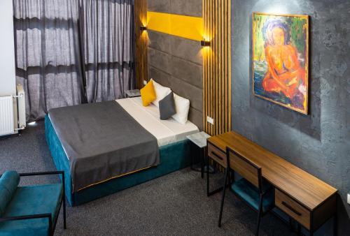 第比利斯BG Palace Hotel的卧室配有一张床,墙上挂有绘画作品