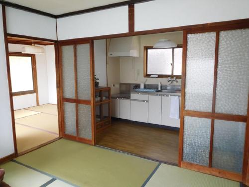 尾道市ゲストハウス尾道ポポー Guesthouse Onomichi Pawpaw的一间设有白色橱柜和木门的大厨房