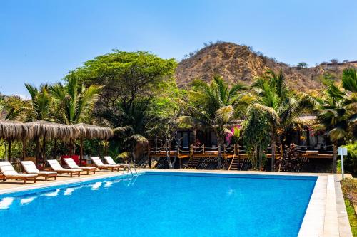 索里托斯Bungalows & Suites Punta Camarón的一个带椅子的游泳池,后方是一座山。