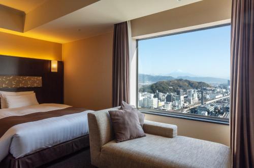 静冈HOTEL GRAND HILLS SHIZUOKA的酒店客房设有一张床和一个大窗户