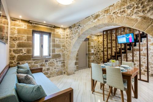 基萨莫斯Agarathos Deluxe Homes的一间设有石墙和桌椅的用餐室