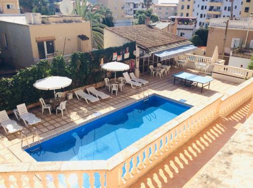 马略卡岛帕尔马圣特尔莫旅馆的一座带椅子和遮阳伞的游泳池位于一座建筑旁边