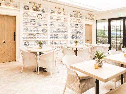 罗斯奈格尔Sandy Mount House的餐厅墙上设有白色桌椅和盘子