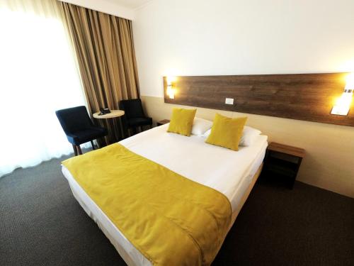 马马亚Zenith - Top Country Line - Conference & Spa Hotel的酒店客房,配有一张带黄色床单的大床