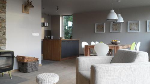 拉罗什-阿登Ardennature vakantiehuizen met privé-sauna的客厅配有两把椅子、一台电视和一张桌子